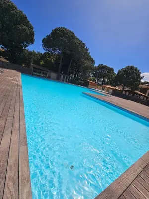 a large blue swimming pool with a wooden deck at Très bel appartement T3 dans résidence hotellière 