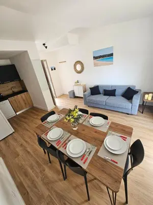a dining table and chairs in a living room at Très bel appartement T3 dans résidence hotellière 
