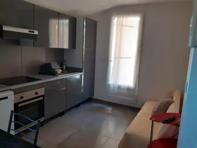 a kitchen with gray cabinets and a window and a couch at Chez Aldo in Ajaccio