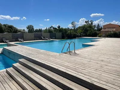a swimming pool with a wooden deck next to a swimming pool at Villa A CASA DI LO in Lecci