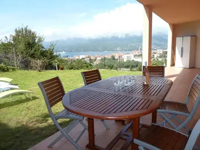a wooden table and chairs on a patio at T3 en rdj pour 6 pers dans résidence avec piscine in Propriano