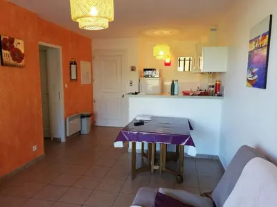 a living room with a table and a kitchen at T3 en rdj pour 6 pers dans résidence avec piscine in Propriano