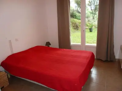 a red bed in a room with a window at T3 en rdj pour 6 pers dans résidence avec piscine in Propriano