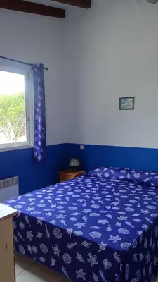 a bedroom with a bed with a blue comforter and a window at Residence Funtanella in Sagone