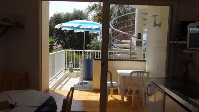 a kitchen with a table and an umbrella on a balcony at Residence Funtanella in Sagone