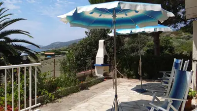 a patio with an umbrella and chairs and a telescope at Residence Funtanella in Sagone