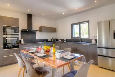 a kitchen with a wooden table and chairs in it at Villa Stella avec piscine entre mer et rivière in Vardiola