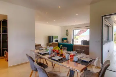 a dining table and chairs in a living room at Villa Stella avec piscine entre mer et rivière in Vardiola