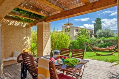 a patio with a table and chairs and a hammock at Maisonnette une chambre 