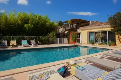 a swimming pool with chairs and a house at Maisonnette une chambre 