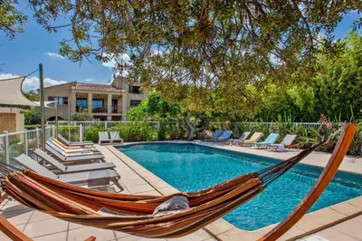 a hammock and chairs next to a swimming pool at Maisonnette une chambre 