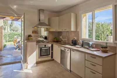 a kitchen with white cabinets and a large window at Maisonnette une chambre 