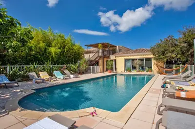 a swimming pool with chairs and a house at Maisonnette 