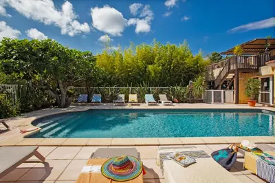 a swimming pool in a backyard with chairs and trees at Maisonnette 