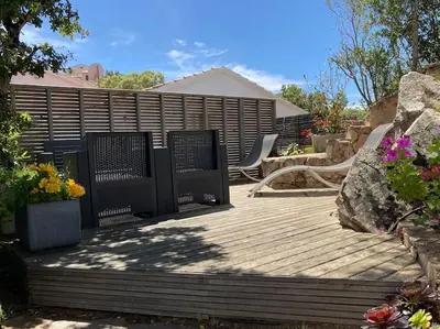 a wooden deck with chairs and flowers on it at Maison avec jardin et parking privé à 300m du centre ville de porto -vecchio in Porto-Vecchio