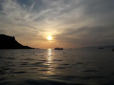 a boat on a body of water with the sunset at Villa T4 à Campomoro corse du sud, 800m plage in Belvédère