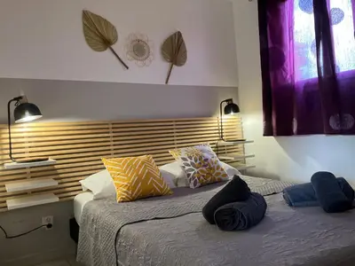 a bedroom with a large bed with colorful pillows at Maison à 2min à pied du centre de porto vecchio in Porto-Vecchio