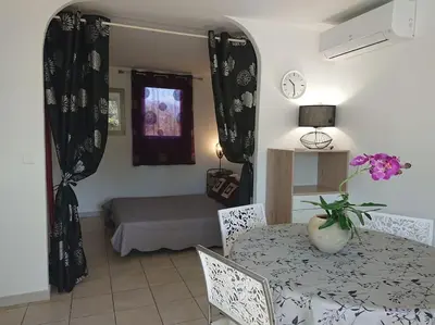 a living room with a table and a bed at Maison à 2min à pied du centre de porto vecchio in Porto-Vecchio