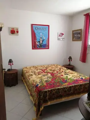 a bedroom with a bed and a poster on the wall at Maison près de la plage in Penta-di-Casinca