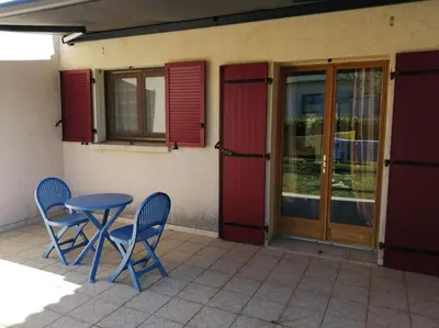 a patio with two chairs and a table and doors at Maison près de la plage in Penta-di-Casinca