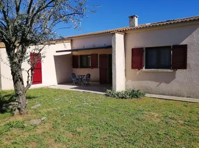 a house with a table and a chair in a yard at Maison près de la plage in Penta-di-Casinca