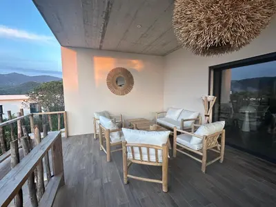 a balcony with chairs and a table and a chandelier at Villa Casa di Simone Pietrosella Corse du Sud in Pietrosella