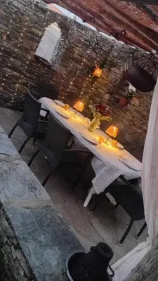 a table in a building with chairs and lights at Maison familiale charmante in Borgo