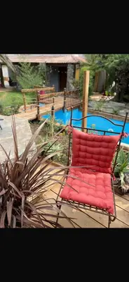 a red chair sitting in front of a pool at Maison familiale charmante in Borgo