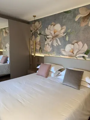 a bedroom with a white bed with a floral wallpaper at Résidence Apa Nera in Calenzana