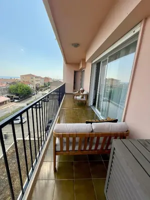 a balcony with a bench and a view of a city at Appartement T4 climatisé, lumineux et vue mer à Solenzara in Sari Solenzara