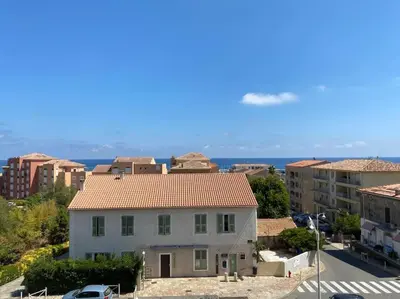 a white house in a city with buildings at Appartement T4 climatisé, lumineux et vue mer à Solenzara in Sari Solenzara