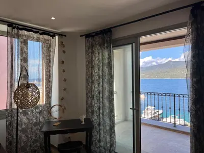 a room with a balcony with a view of the ocean at Résidence Cas’Antica in Propriano