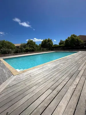 a large swimming pool with a wooden deck at Porto vecchio Résidence Don Andria T2 in Lecci
