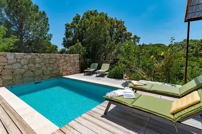a swimming pool with a deck and chairs on a wooden deck with at Locations de La Casette d'Araggio in Porto-Vecchio