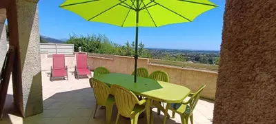 a green table with chairs and an umbrella on a balcony at Entre mer et montagne in Monte