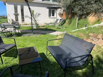 a group of chairs and an umbrella in the grass at Rez de villa golfe de lava in Appietto