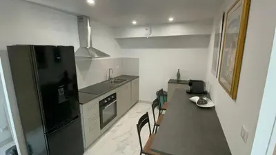 a kitchen with a black refrigerator and a table and chairs at Rez de villa golfe de lava in Appietto
