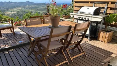 a wooden table and chairs on a deck with a grill at Maison de famille in Vallecalle
