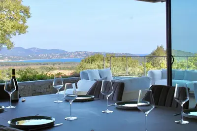 a table with chairs and wine glasses on a balcony at Villa A Pinetta Villata in Sainte-Lucie de Porto-Vecchio