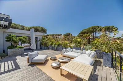 a patio with white furniture on a wooden deck at Villa A Pinetta Villata in Sainte-Lucie de Porto-Vecchio