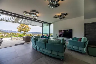 a living room with green chairs and a large window at Villa A Pinetta Villata in Sainte-Lucie de Porto-Vecchio