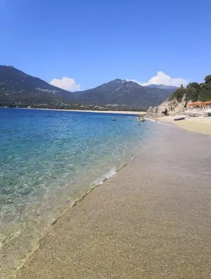 a beach with blue water and mountains in the background at Appartement vue mer Les hameaux de Propriano à Propriano in Propriano