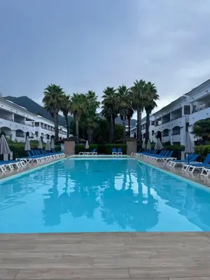 a large swimming pool with chairs and palm trees at Appartement T3 les pieds dans l'eau in Moriani Plage