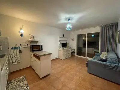 a living room with a couch and a kitchen at Appartement T3 les pieds dans l'eau in Moriani Plage