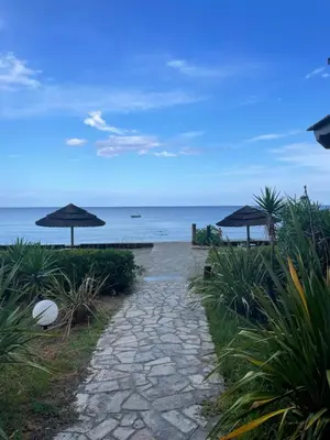 a walkway with umbrellas next to the ocean at Appartement T3 les pieds dans l'eau in Moriani Plage