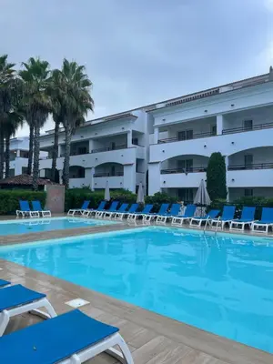 a large swimming pool with chairs and a building at Appartement T3 les pieds dans l'eau in Moriani Plage