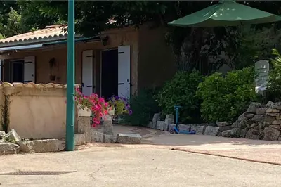 a house with an umbrella and flowers in front of it at Mini villa de charme. in Zonza