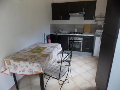 a kitchen with a table and a table and chairs at Mini villa de charme. in Zonza