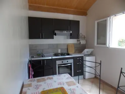 a kitchen with black cabinets and a stove at Mini villa de charme. in Zonza