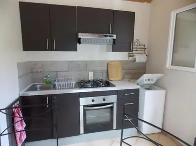 a kitchen with black cabinets and a stove and a refrigerator at Mini villa de charme. in Zonza